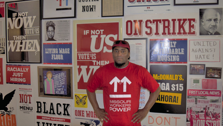 Terrence Wise stands in front of a wall of campaign posters at Missouri Workers Power’s Kansas City headquarters. (Thomas White/The Beacon)