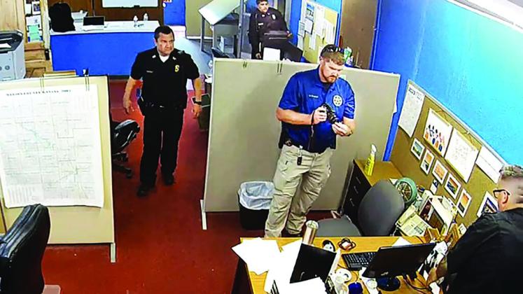  A lawsuit says Marion Police Chief Gideon Cody, top left, spearheaded the Aug. 11 raid of the Marion County Record in retaliation against the journalists who worked there. Reporter Deb Gruver’s desk appears at the bottom right. She filed the lawsuit in federal court (Marion County Record screen capture of surveillance video).
