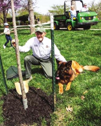 Conservation Commissioner Mark McHenry and his dog, Truman, at the tulip tree planted in McHenry’s honor at the Kansas City Arbor Day celebration at Loose Park on April 23.