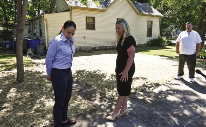 U.S. Rep. Sharice Davids, left, talks with Olathe’s distribution compliance manager Megan Spence on Thursday outside the home of Jerry Land (right) who recently had a lead pipe in his yard replaced by the city. photo/Carlos Moreno/KCUR.