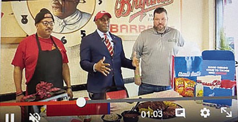 KCMO Mayor Quinton Lucas (center) at Arthur Bryant’s Barbecue today (Thursday) showing an array of items he has wagered with Cincinnati Mayor Aftab Pureval. photo/screenshot