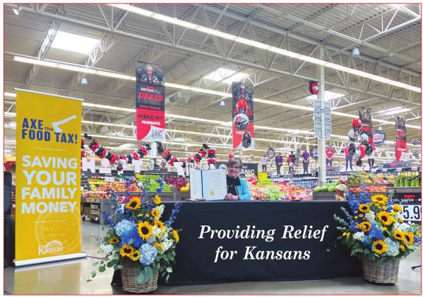 Seated at a local grocery store, Kansas Governor Laura Kelly displays the “Axe the Food Tax” Bill she signed on Wednesday.