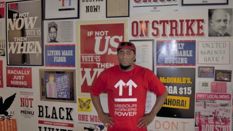 Terrence Wise stands in front of a wall of campaign posters at Missouri Workers Power’s Kansas City headquarters. (Thomas White/The Beacon)