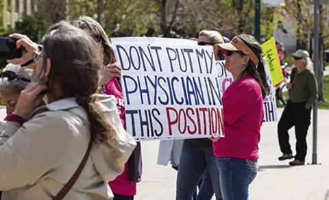 A protester at a Planned Parenthood Great Northwest rally in Boise, Idaho, holds up a sign about the EMTALA case on April 21, 2024 (Otto Kitsinger/Idaho Capital Sun).