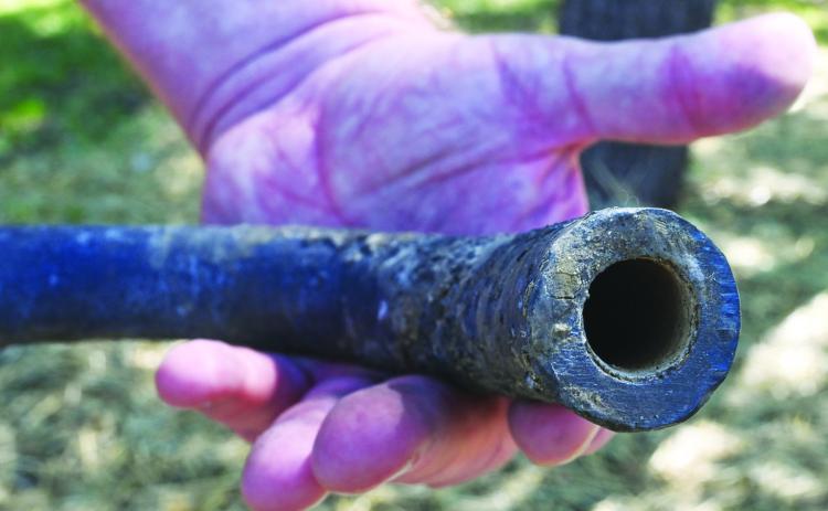 A piece of lead pipe removed from Jerry Land’s yard in Olathe shows a layer of lining inside the pipe that indicates the city’s water supply provided a thin film that prevented the pipe from leeching lead into the home’s water .photo(Carlos Moreno/KCUR).