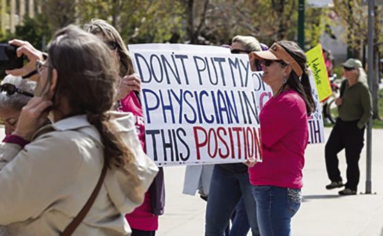 A protester at a Planned Parenthood Great Northwest rally in Boise, Idaho, holds up a sign about the EMTALA case on April 21, 2024 (Otto Kitsinger/Idaho Capital Sun).