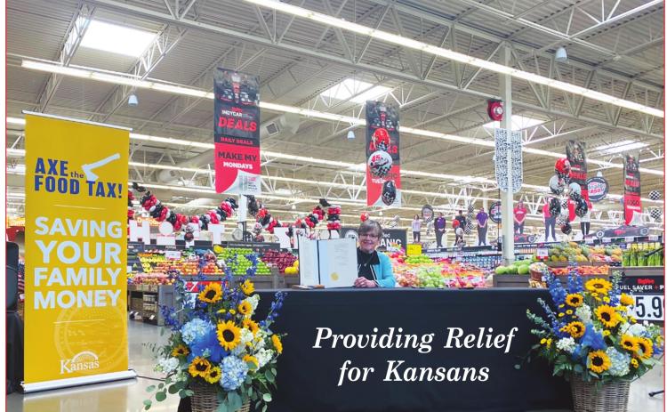 Seated at a local grocery store, Kansas Governor Laura Kelly displays the “Axe the Food Tax” Bill she signed on Wednesday.