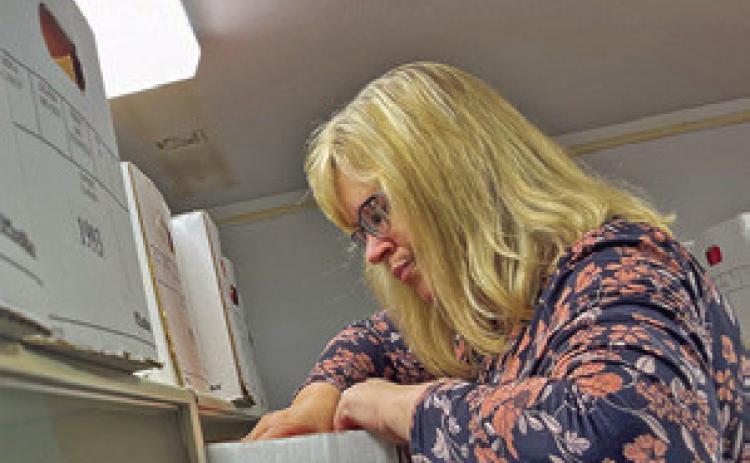 Iron County Circuit Clerk Sammye White balances on a stepladder as she searches for an old marijuana case in the office storage room in Ironton. (Rebecca Rivas/Missouri Independent)